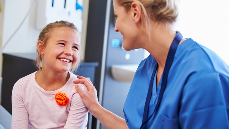 Resident placing hand on happy child female patient