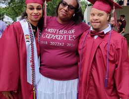 Luann smiling proudly standing with her two high school graduates, Diviana and Alexavier, who are in their graduation regalia